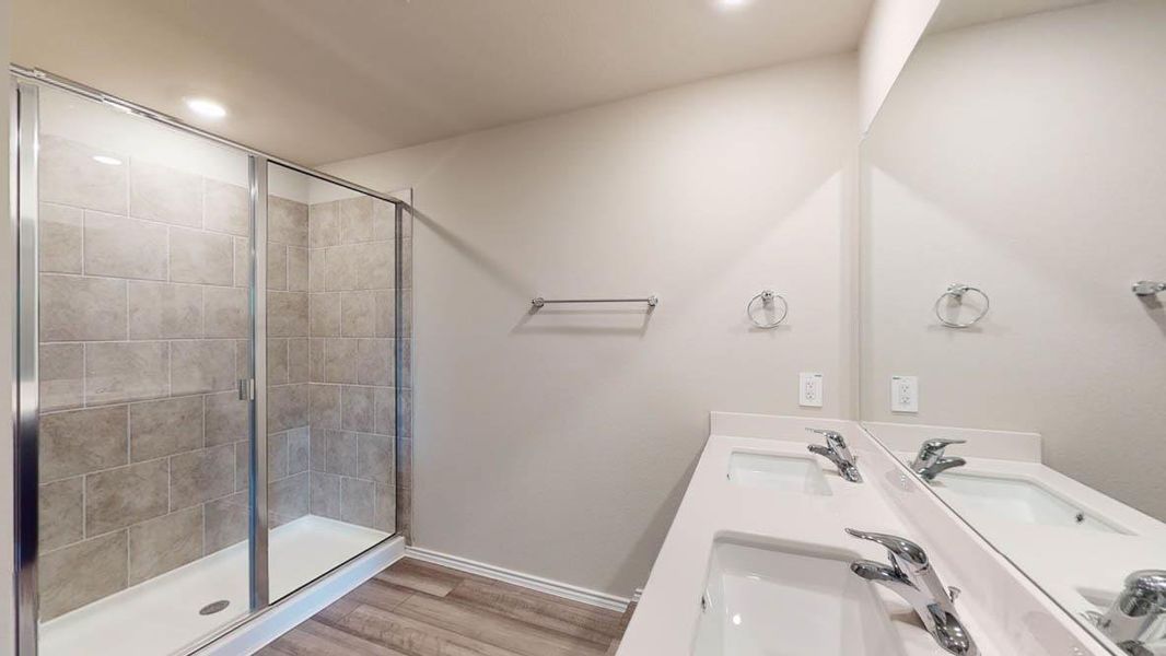 Bathroom featuring double vanity, a stall shower, light wood-type flooring, and recessed lighting