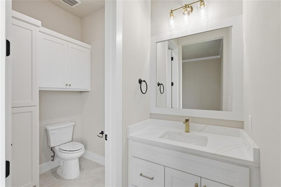 White vanity with a rectangular undermount sink and brass-finish faucet