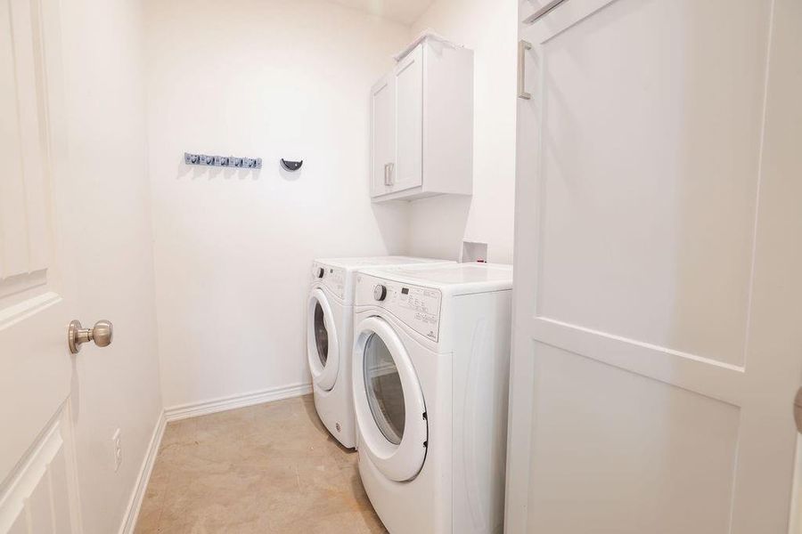 Laundry room with cabinet space, washer and dryer, and light tile patterned floors