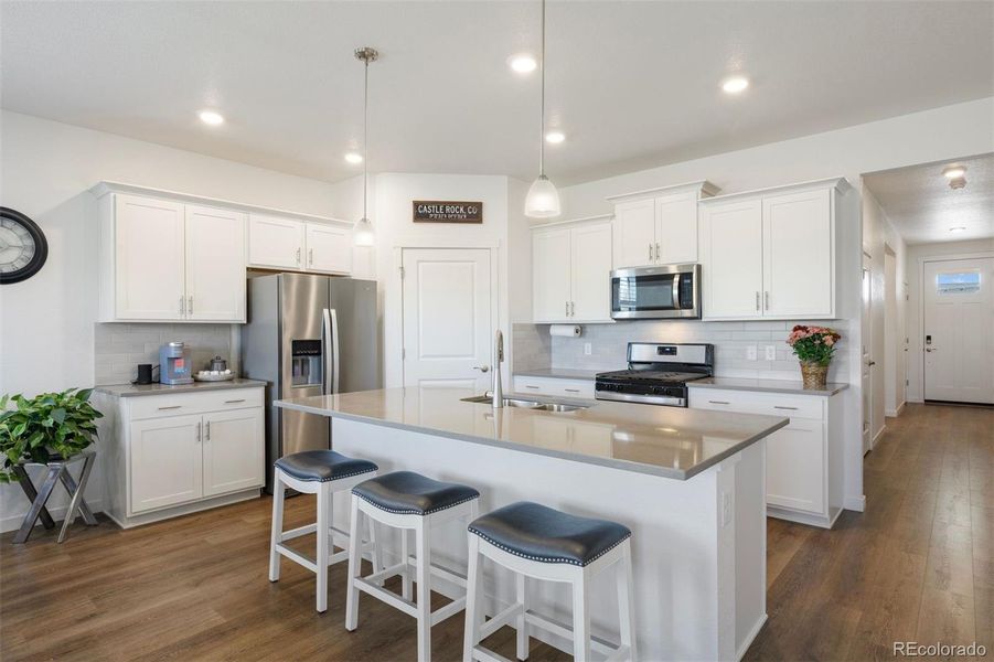 Bright, open kitchen with a large quartz island, and breakfast bar seating.