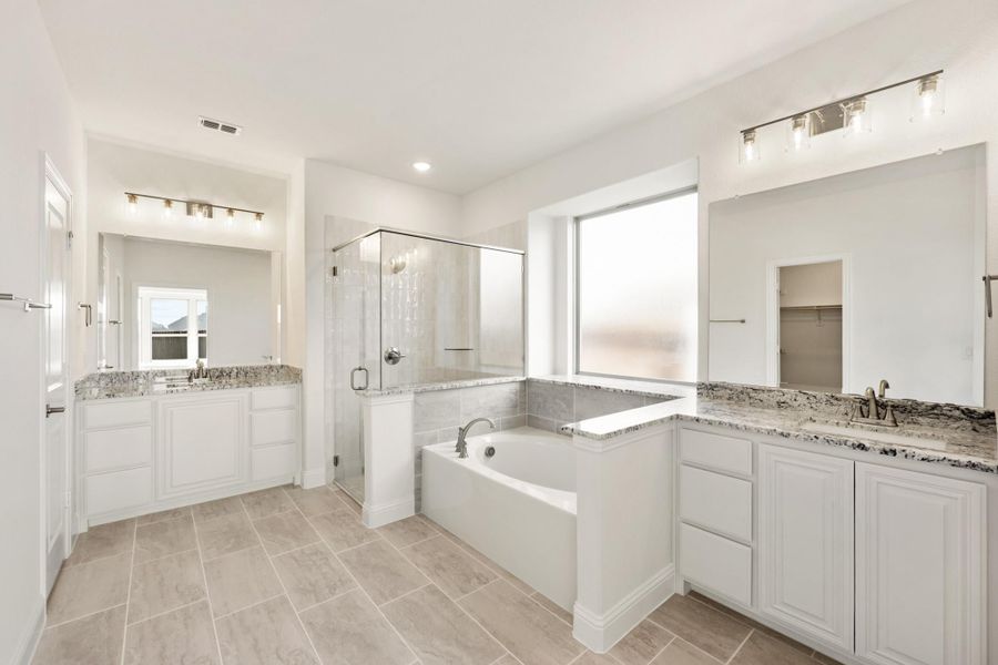 Master bathroom with dual vanities, soaking tub, glass shower, and granite countertops on white cabinets Master bathroom with dual vanities, soaking tub, glass shower, and granite countertops on white cabinets