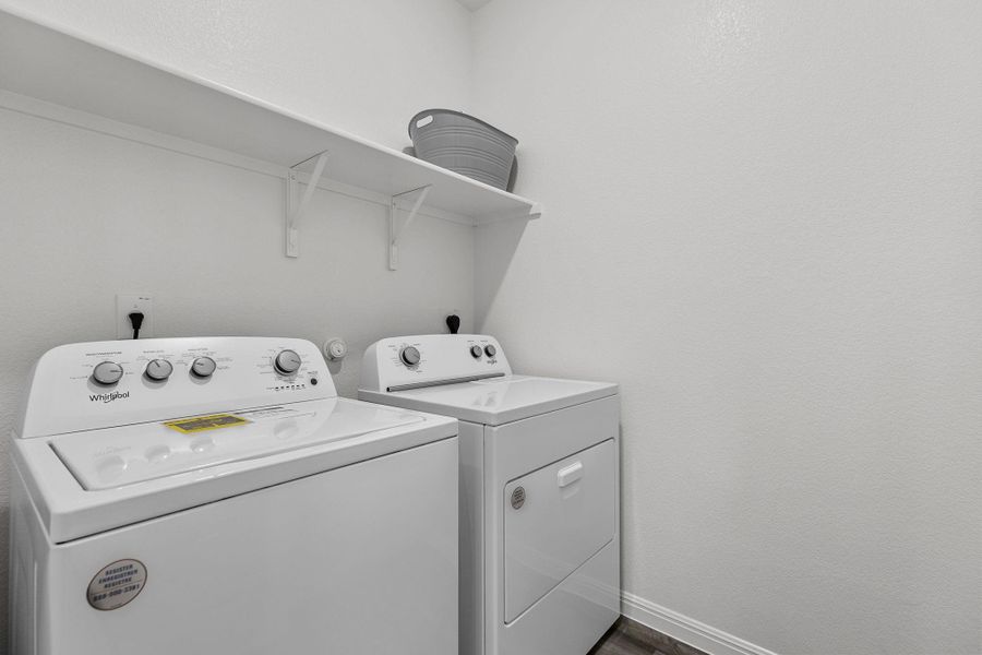 Laundry area with washing machine and dryer, a textured wall, and dark wood-style floors Laundry area with washing machine and dryer, a textured wall, and dark wood-style floors