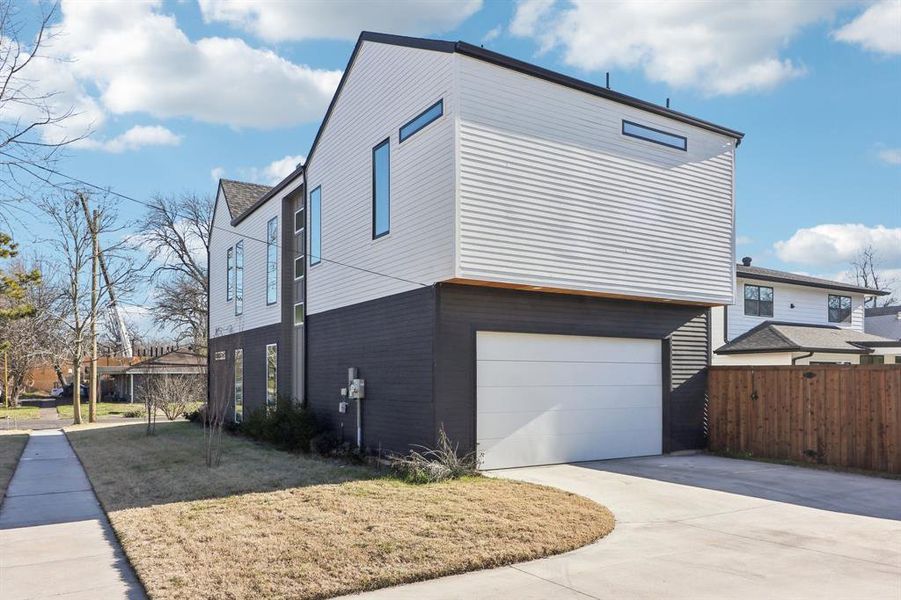 View of side of property with a garage and a lawn