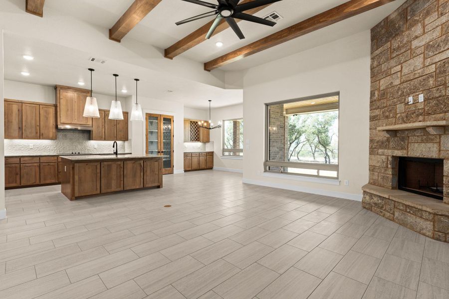 Kitchen featuring open floor plan, brown cabinets, backsplash, pendant lighting, and a center island with sink Kitchen featuring open floor plan, brown cabinets, backsplash, pendant lighting, and a center island with sink