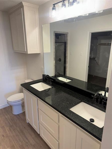 Bathroom with vanity, toilet, walk in shower, and hardwood / wood-style floors