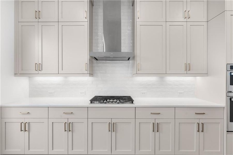 Kitchen with wall chimney exhaust hood, backsplash, white cabinets, light stone counters, and stainless steel appliances