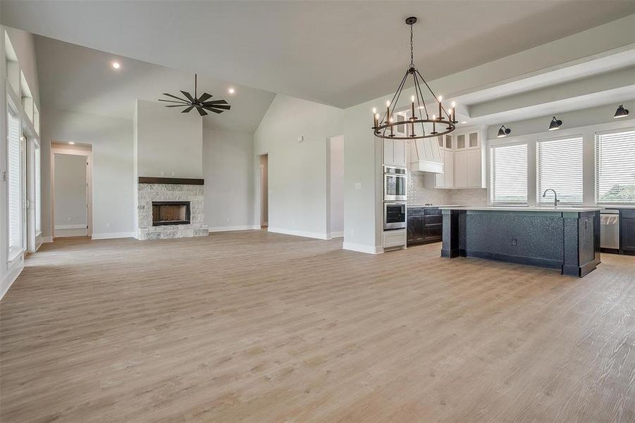 Unfurnished living room featuring a fireplace, sink, light wood-type flooring, and an inviting chandelier