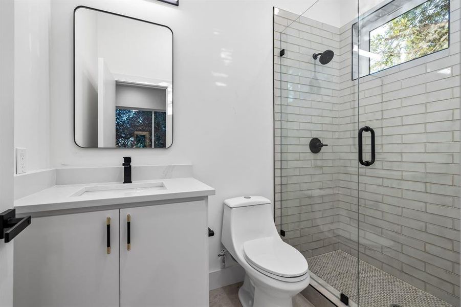 Bathroom with vanity, toilet, and a shower with shower door