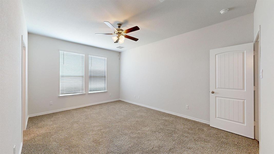 Empty room with light colored carpet and ceiling fan