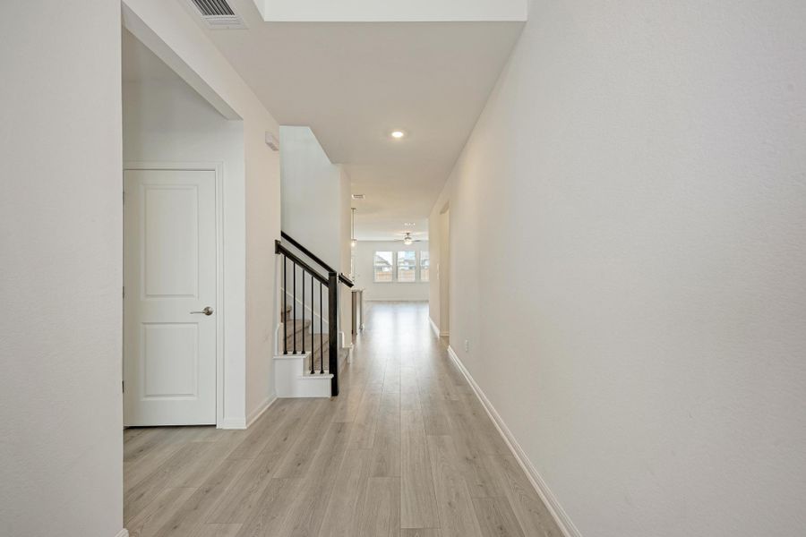 A graceful entry hall welcomes, showcasing modern flooring and a stylish staircase leading to sun-filled spaces.