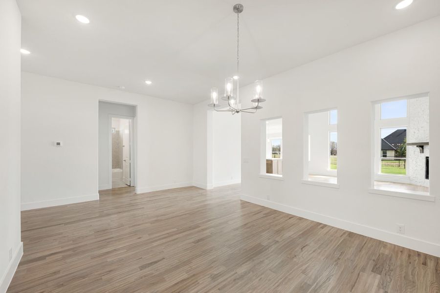 Open dining room with wood-look floors, chandelier, and large windows with backyard views Open dining room with wood-look floors, chandelier, and large windows with backyard views