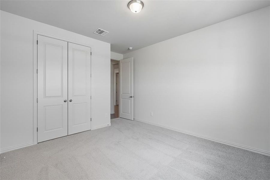 Unfurnished bedroom featuring light carpet and a closet Unfurnished bedroom featuring light carpet and a closet