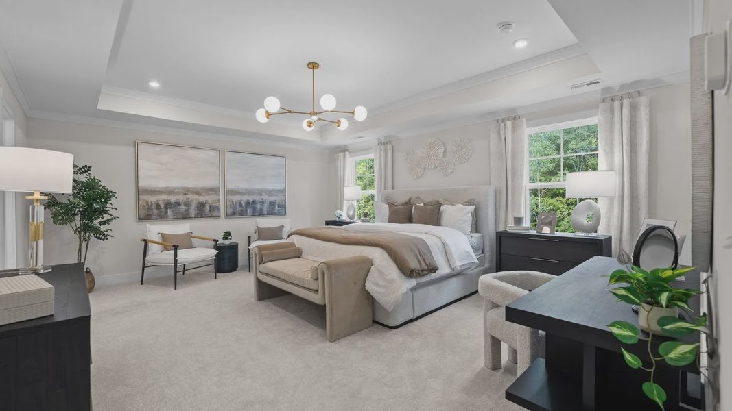 Grand primary bedroom with seating area, elevated tray ceiling, & large windows in the Jordan Design by DRB Homes in York, SC