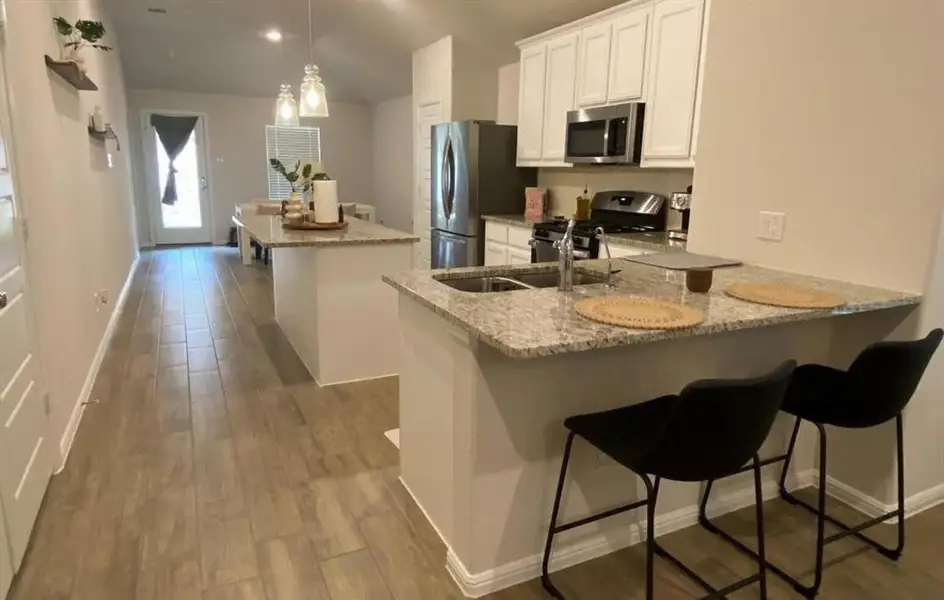 Kitchen featuring white cabinets, light wood-type flooring, a breakfast bar, recessed lighting, and vaulted ceiling Kitchen featuring white cabinets, light wood-type flooring, a breakfast bar, recessed lighting, and vaulted ceiling