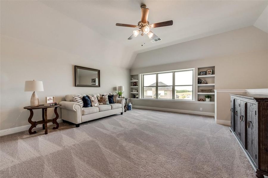 HUGE Bonus room featuring built-in shelves, vaulted ceiling, and ceiling fan