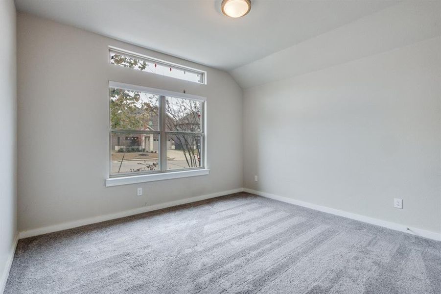 Unfurnished room with lofted ceiling and carpet flooring Unfurnished room with lofted ceiling and carpet flooring