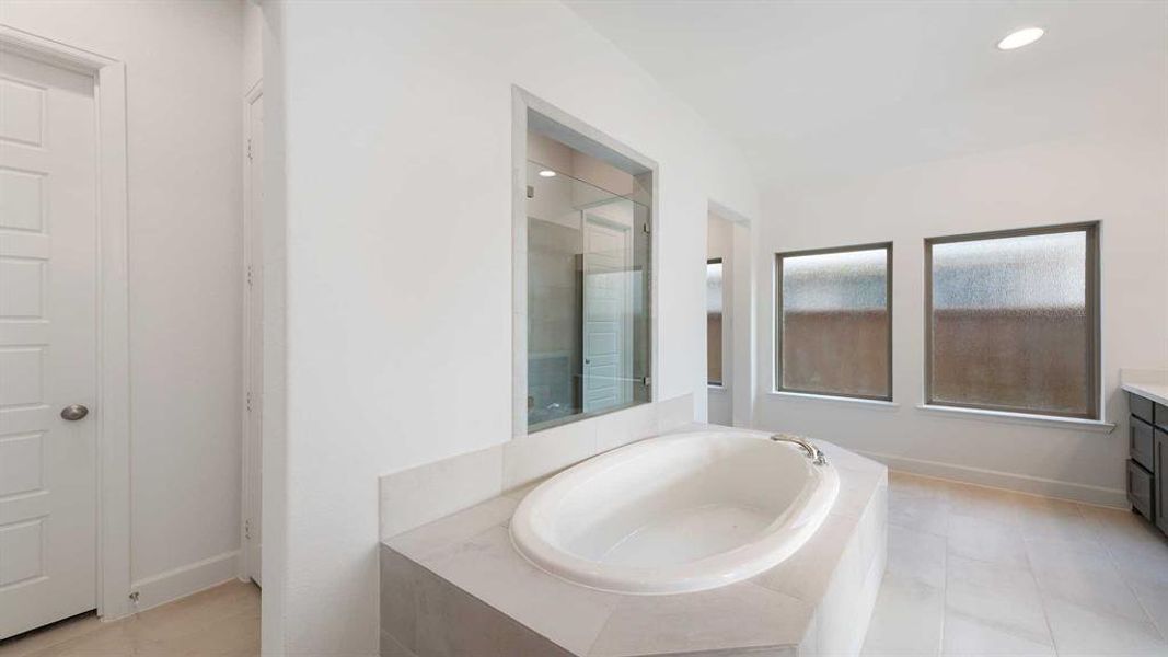 Bathroom featuring tile patterned flooring, separate shower and tub, and vanity