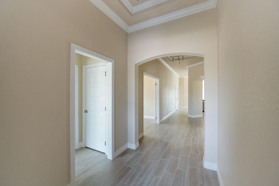 Hall with ornamental molding, arched walkways, and wood tiled floors Hall with ornamental molding, arched walkways, and wood tiled floors