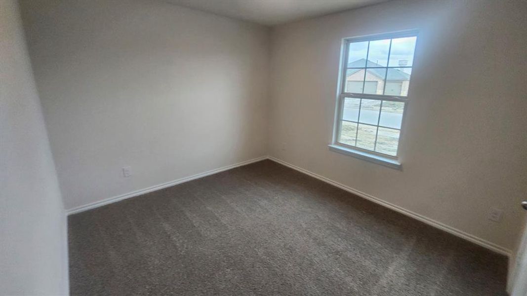 Neutral-toned room featuring a single window with grid panes, textured wall finishes, and a gray carpeted floor