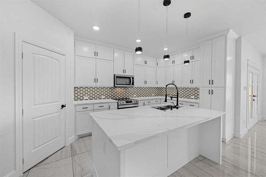 Kitchen with a kitchen island with sink, tasteful backsplash, sink, appliances with stainless steel finishes, and white cabinets