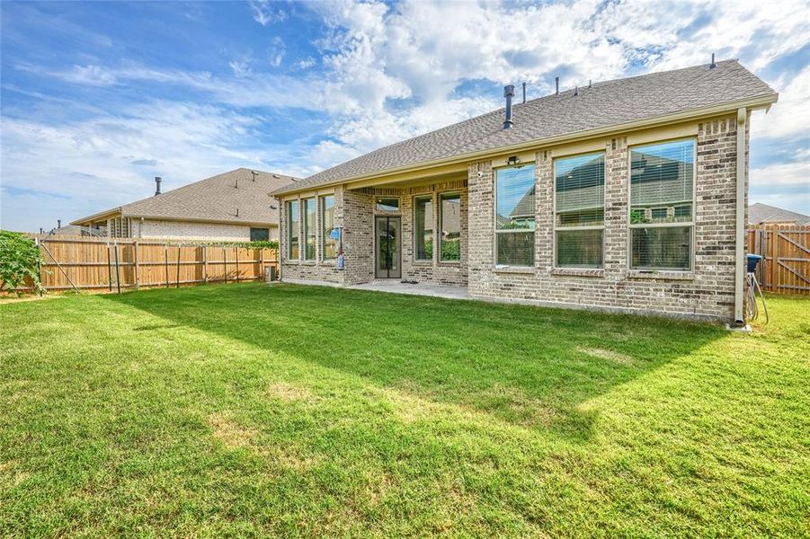 Back of property with a patio area, brick siding, a fenced backyard, and a shingled roof Back of property with a patio area, brick siding, a fenced backyard, and a shingled roof