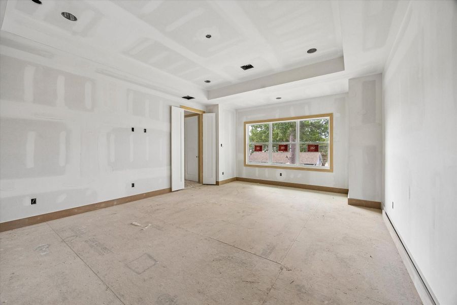 Spacious primary suite with tray ceiling detail and recessed lighting for a refined architectural touch. Oversized window brings in natural light while the generous footprint allows for a true retreat with room for a sitting area. Spacious primary suite with tray ceiling detail and recessed lighting for a refined architectural touch. Oversized window brings in natural light while the generous footprint allows for a true retreat with room for a sitting area.