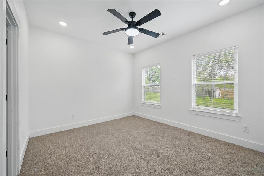 Carpeted spare room with ceiling fan, baseboards, visible vents, and recessed lighting