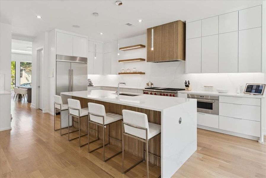 Kitchen with modern cabinets, white cabinets, a kitchen bar, light wood finished floors, and recessed lighting