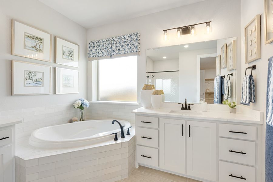 Master bathroom with soaking tub, white subway tile surround, and white vanity with large mirror