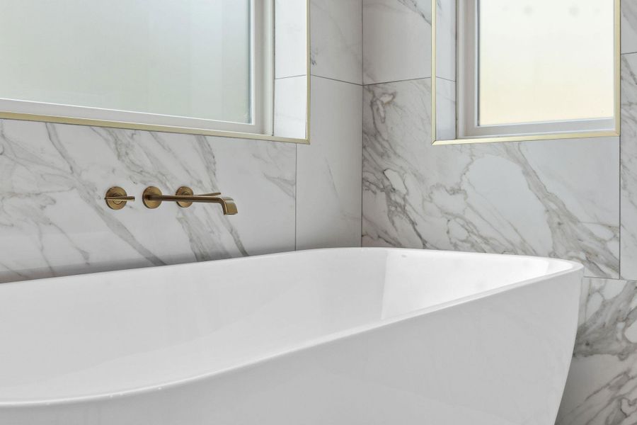 Elegance defines this space featuring a modern soaking tub against tile walls.