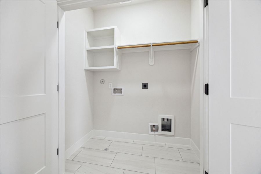 Efficiently designed utility closet with ample storage and convenient washer/dryer hookups.