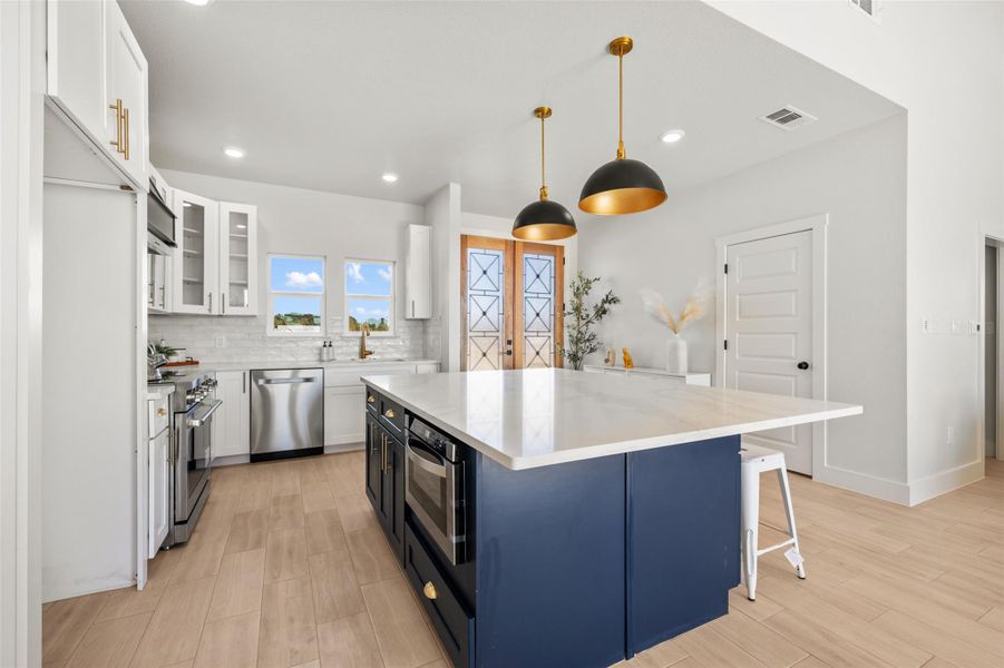 Kitchen with white cabinets, decorative light fixtures, a breakfast bar area, light stone countertops, and recessed lighting