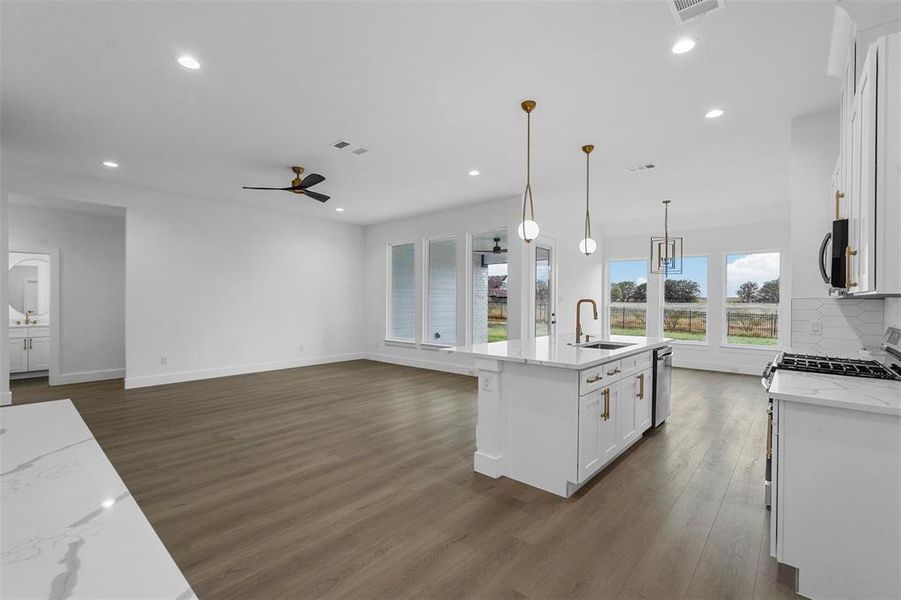 Kitchen with dark wood finished floors, white cabinets, ceiling fan, recessed lighting, and open floor plan Kitchen with dark wood finished floors, white cabinets, ceiling fan, recessed lighting, and open floor plan
