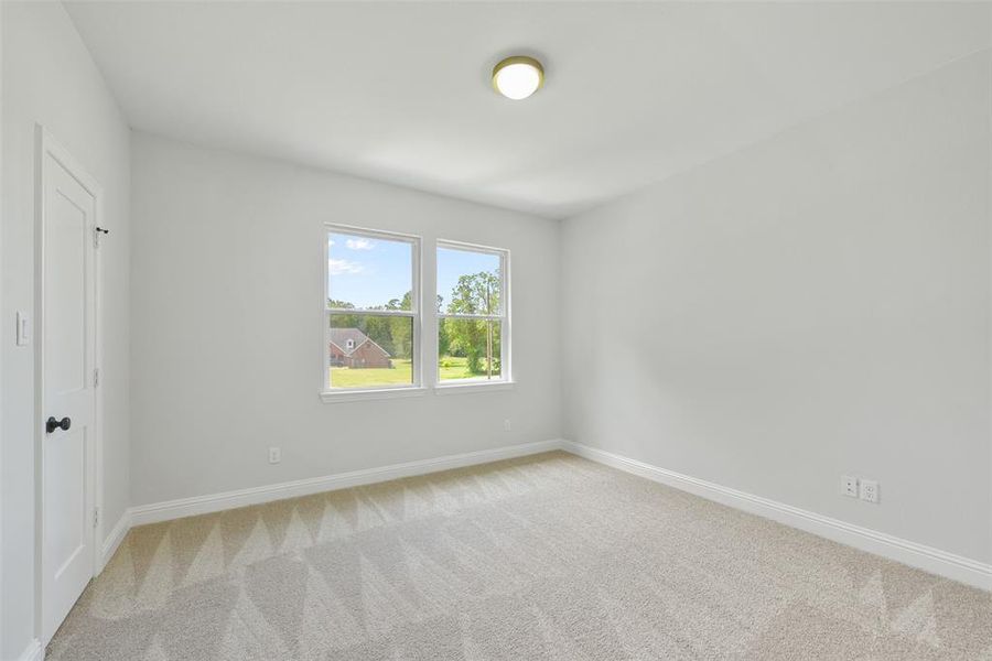 Secondary bedroom is a bright, clean room featuring plush carpeting, two large windows offering natural light, and a fresh neutral color palette, perfect for personalizing to your taste.