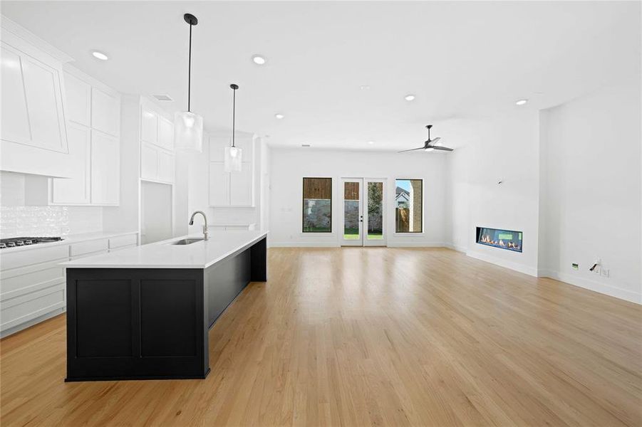 Kitchen featuring white cabinetry, pendant lighting, dark cabinets, recessed lighting, and a glass covered fireplace Kitchen featuring white cabinetry, pendant lighting, dark cabinets, recessed lighting, and a glass covered fireplace