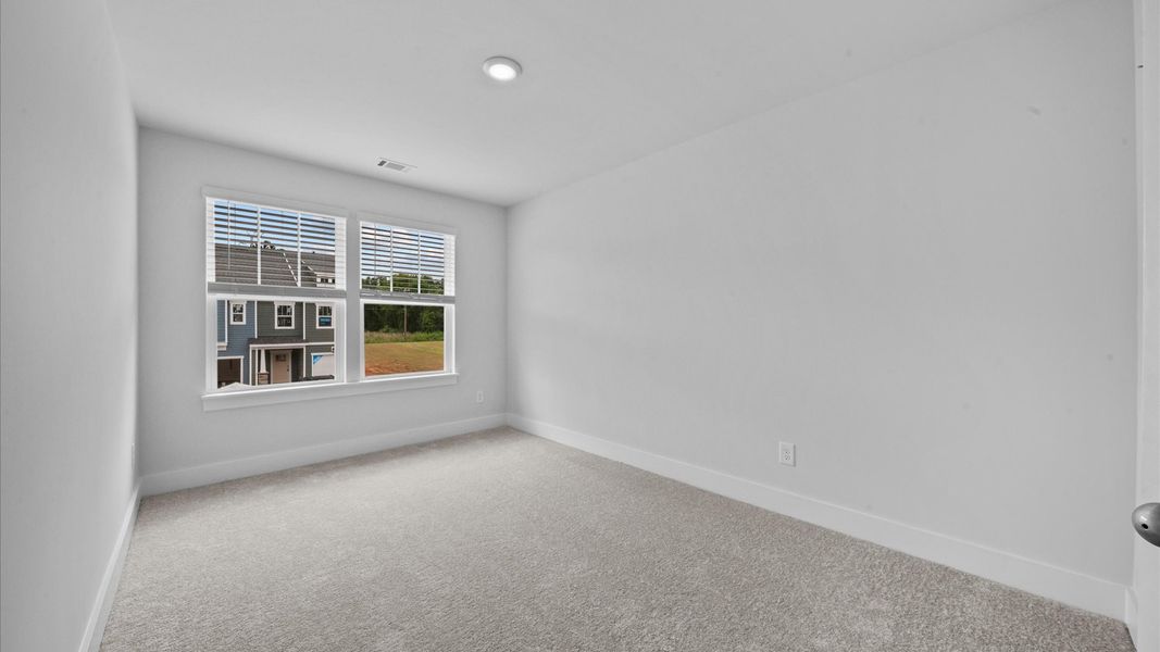 Carpeted bedroom with large windows in two story townhome at Ransdell Pointe by DRB Homes in Spartanburg, SC