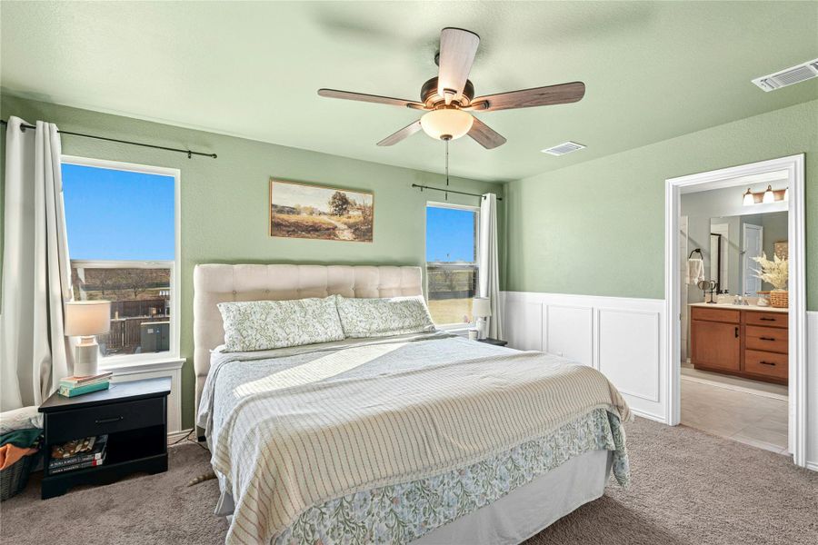 Primary Bedroom features carpet, ensuite bathroom, a wainscoted wall, a ceiling fan, and a decorative walls.