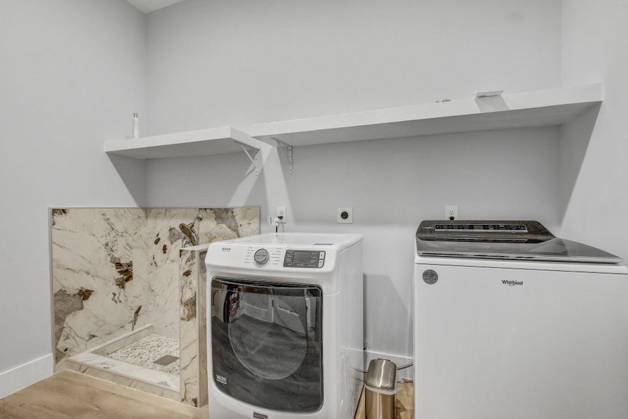 Washroom with washer and clothes dryer and baseboards