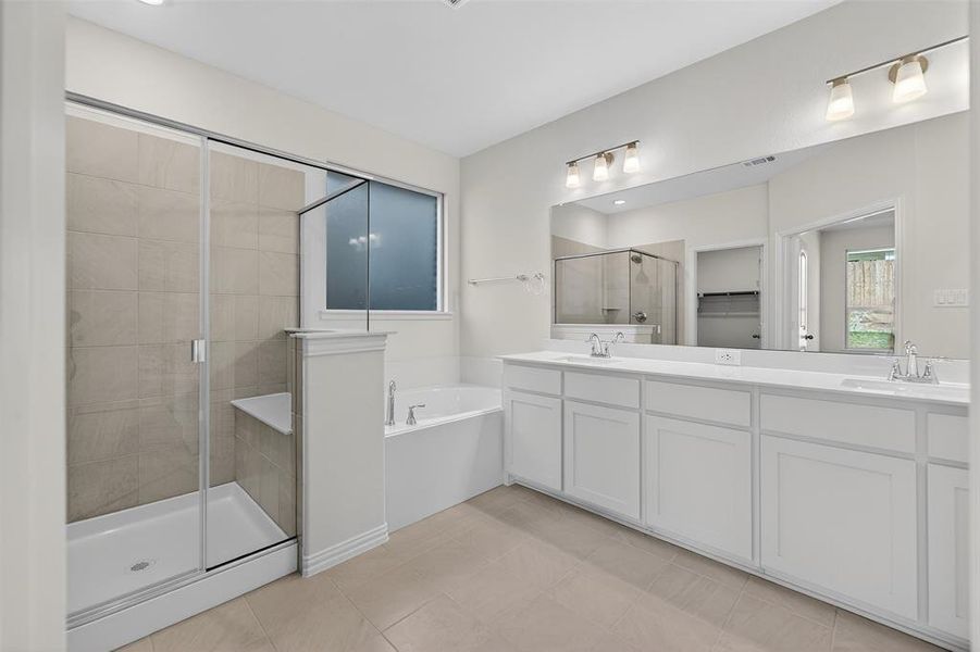 Bathroom with a stall shower, double vanity, a bath, a walk in closet, and light tile patterned floors