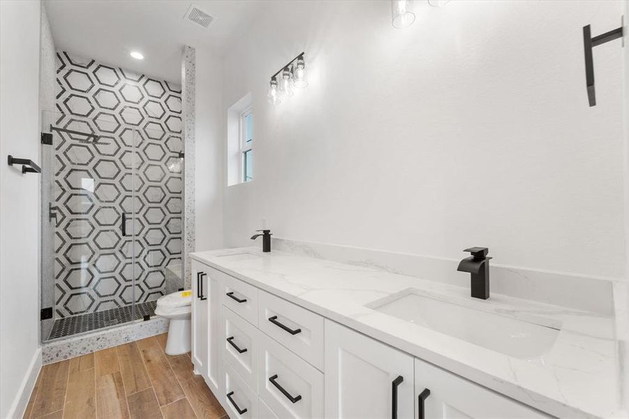 Primary bathroom with dual sinks, plenty of vanity storage and a walk-in shower with a glass door enclosure.