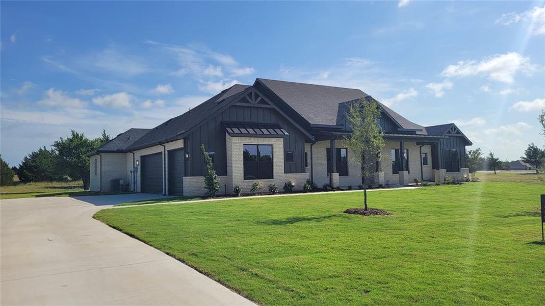 Contemporary ranch-style home featuring a light-colored brick facade and dark vertical siding accents