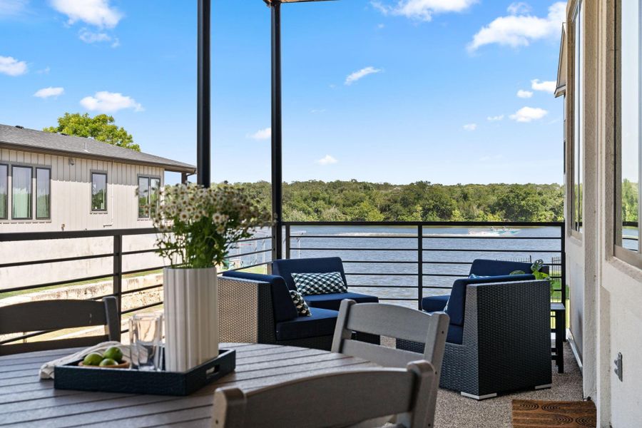 This photo showcases a large balcony overlooking a serene waterfront and offering a scenic view of a tranquil lake and lush greenery. Ideal for relaxation and entertaining.