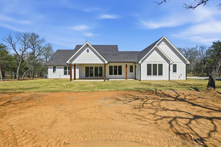 Rear view of property featuring covered porch, a yard, board and batten siding, and a shingled roof
