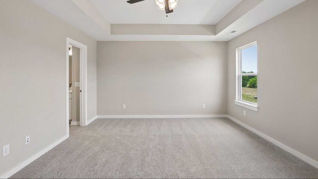 Bedroom with tray ceiling, windows, and ceiling fan