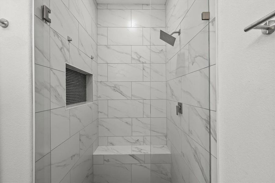 Bathroom with a shower stall and a textured wall