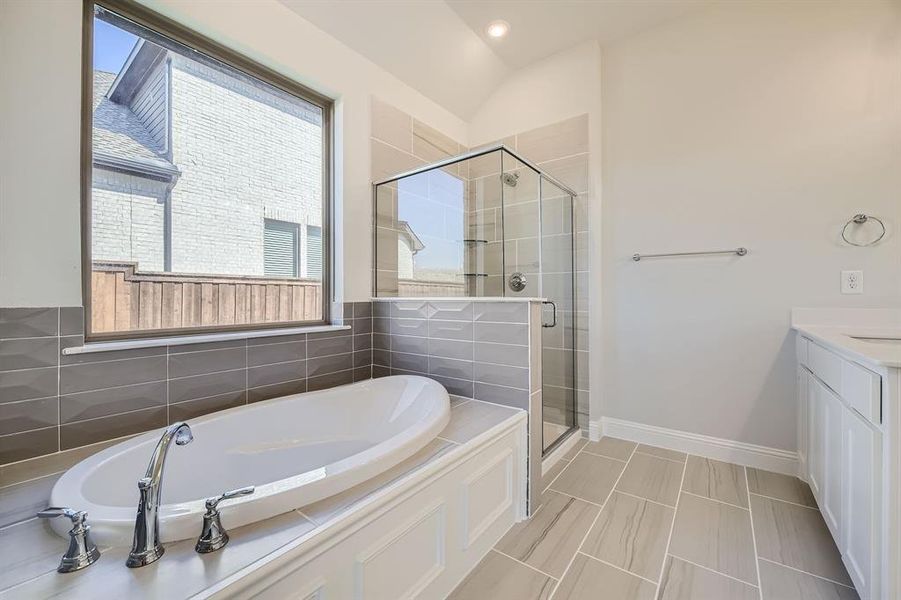 Bathroom with vanity, vaulted ceiling, and plus walk in shower