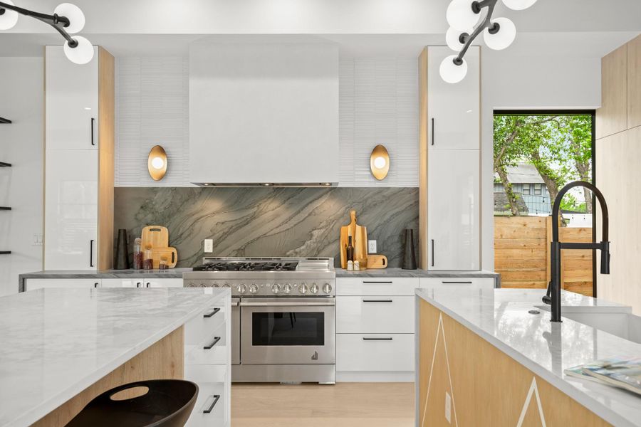 Dual tone kitchen with light stone countertops, double oven range, modern cabinets, dual tone cabinetry, and ventilation hood