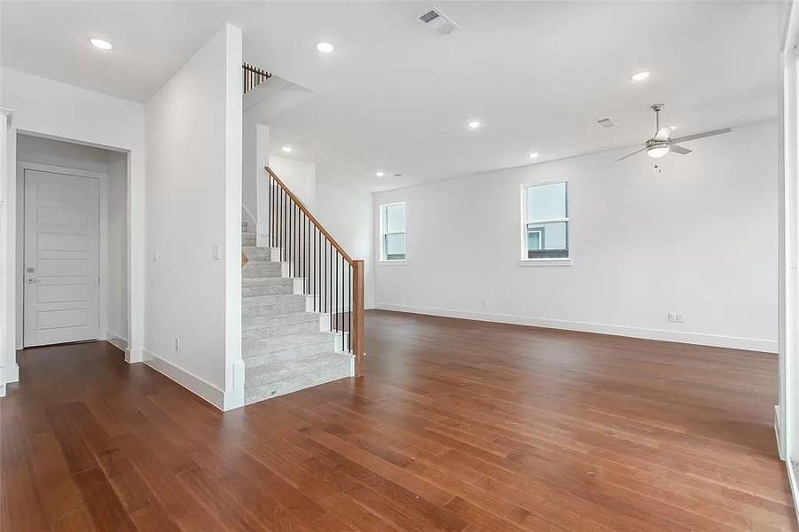 Unfurnished living room featuring ceiling fan and dark hardwood / wood-style flooring