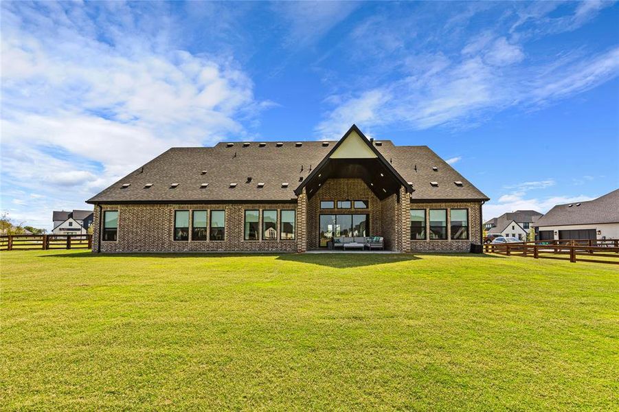 Back of property with a fenced backyard, brick siding, a patio area, and a shingled roof