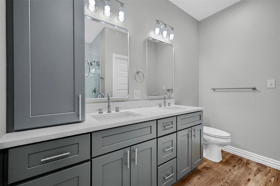 Bathroom featuring hardwood / wood-style flooring, vanity, toilet, and walk in shower